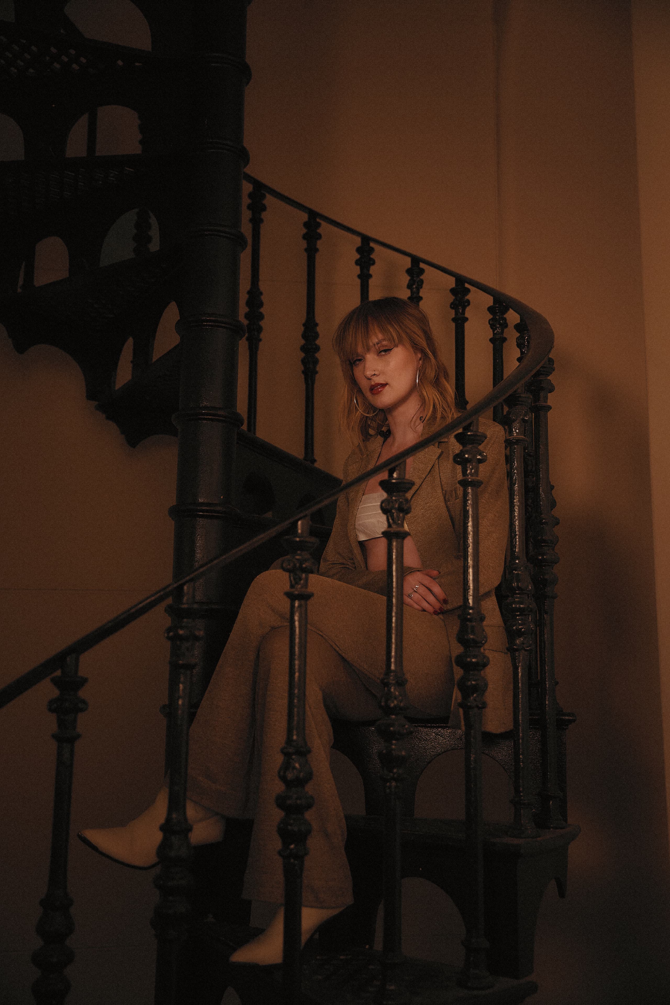 Gretta Ray seated on a spiral staircase at the State Library of Victoria during her live performance for Amazon Music.
