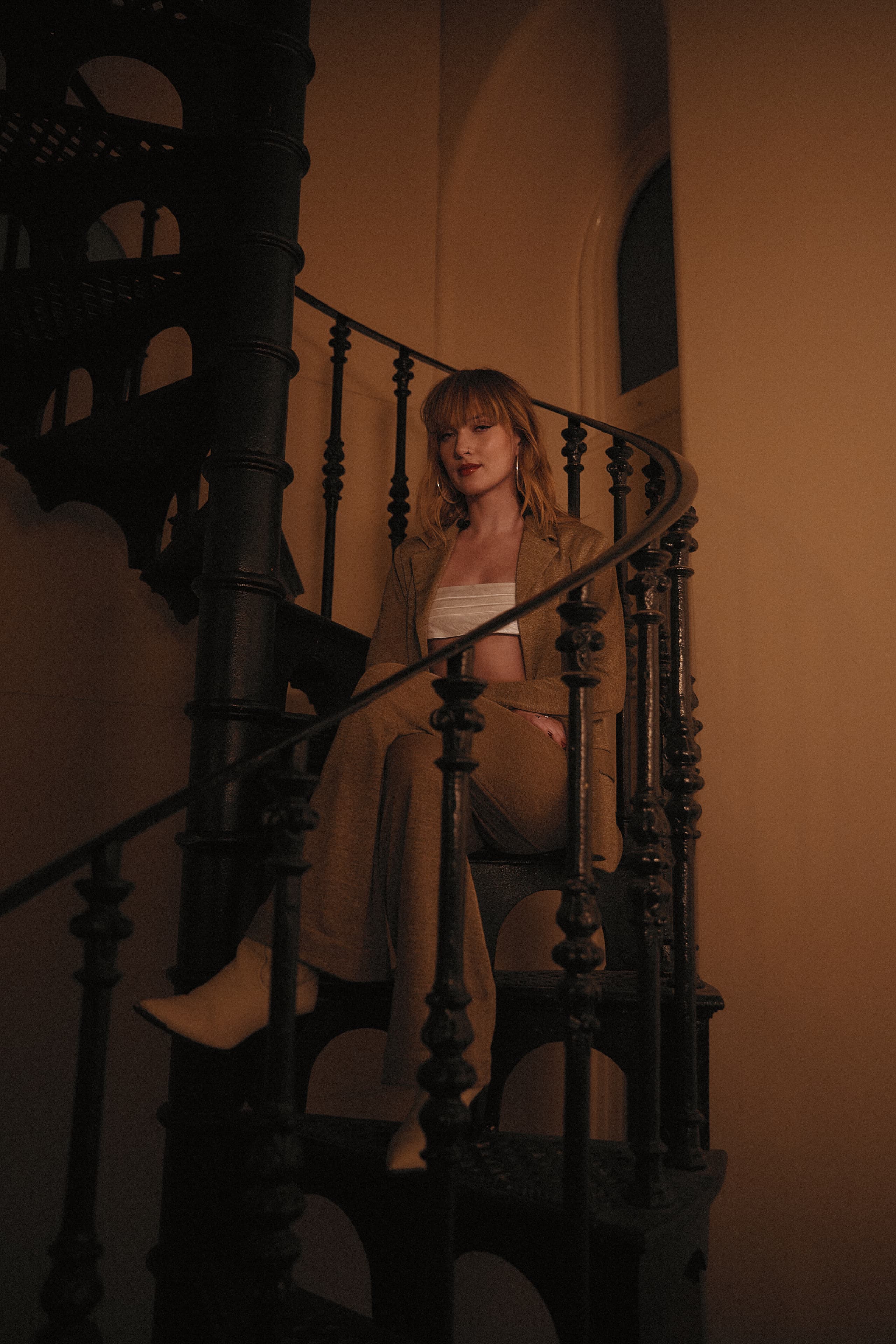 Gretta Ray seated on a spiral staircase at the State Library of Victoria during filming for Amazon Music